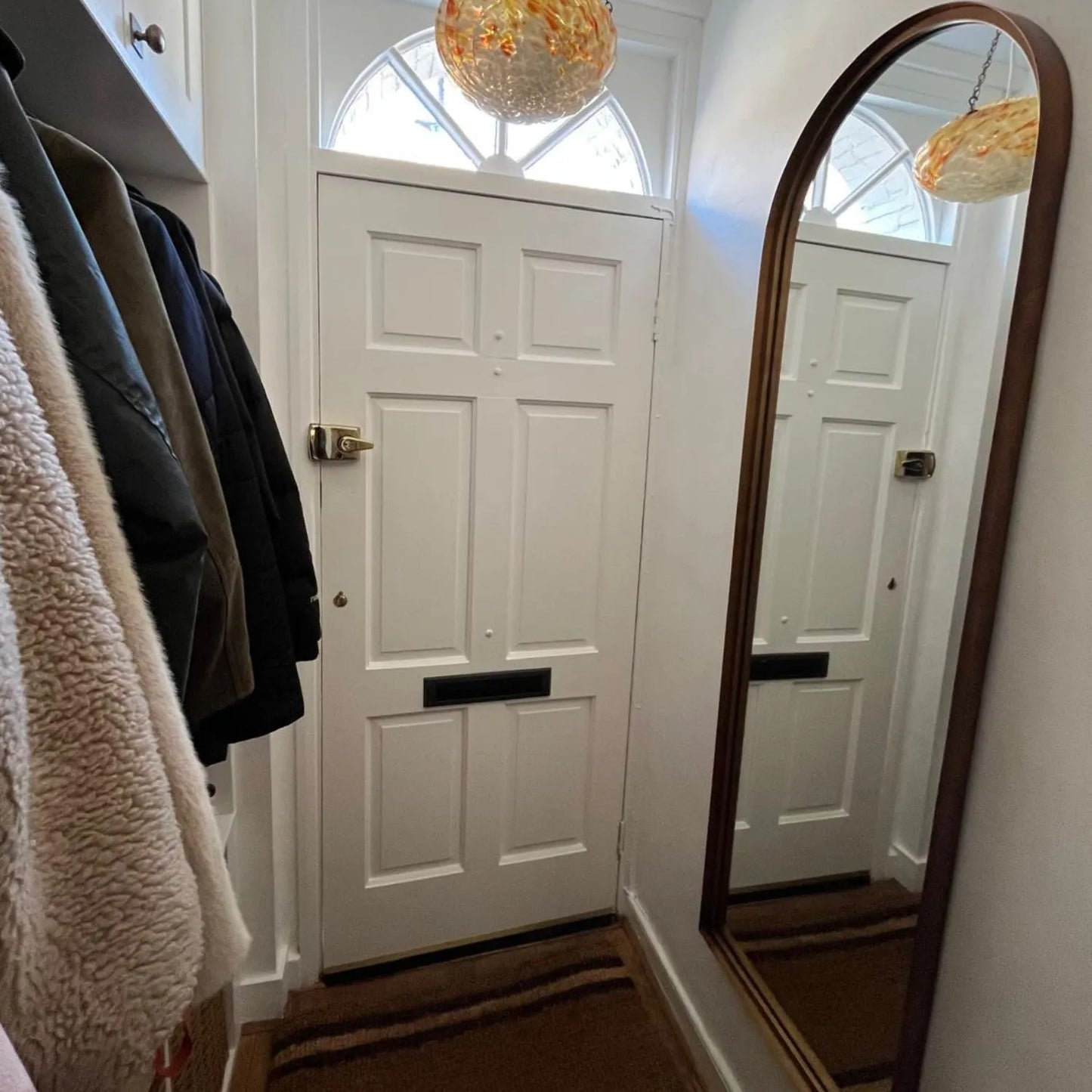 Full Length Aged Bronze Channel Frame Arched Wall Mirror beside a white front door in a customer hallway | Click Style