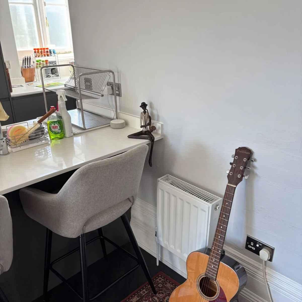 Shelf-Sitter Jazz Saxophonist Resin Ornament – Sitting Musician Sculpture 38x17x11cm – displayed on a kitchen worktop beside an acoustic guitar in a real customer’s home | Click Style