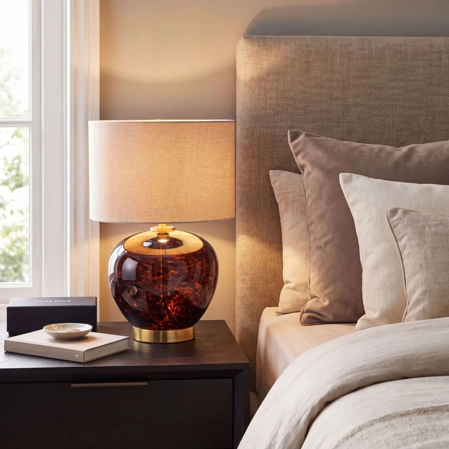 Amber & Brown Tortoiseshell Glass Table Lamp with Natural Linen Shade styled on a bedside table in a contemporary neutral bedroom 44x30x30cm | Click Style