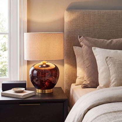 Amber & Brown Tortoiseshell Glass Table Lamp with Natural Linen Shade styled on a bedside table in a contemporary neutral bedroom 44x30x30cm | Click Style