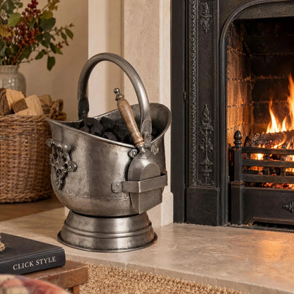 Antique Pewter Effect Silver Coal Bucket with Wooden-Handled Shovel – Ornate Steel Fireside Coal Scuttle 44x30x28cm – Filled with Coal Beside Traditional Stone Fireplace with Shovel Displayed Separately | Click Style
