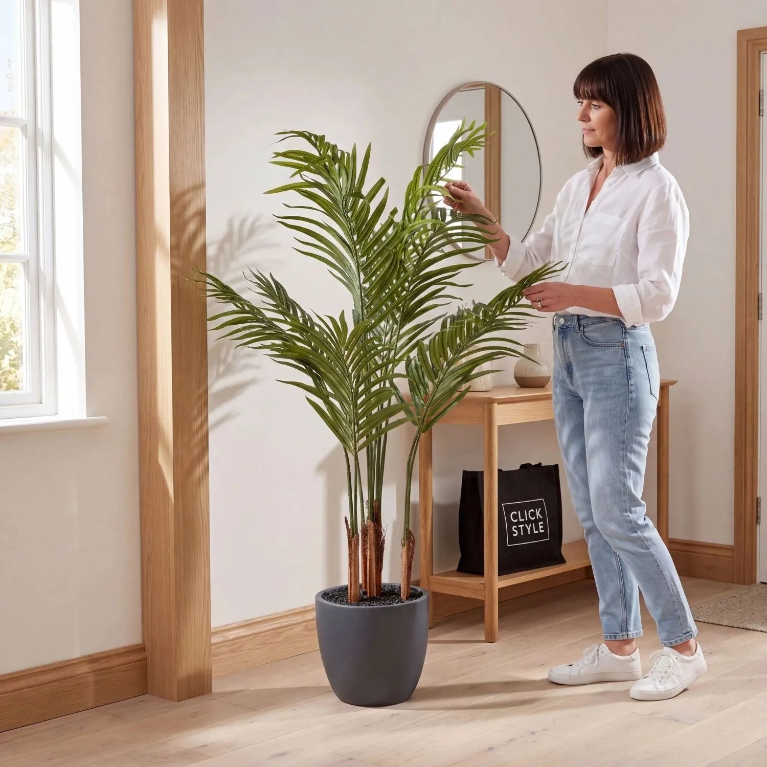 Artificial Areca Palm Plant with Dark Grey Pot – Tall Realistic Indoor Faux Palm 120x80x80cm styled in a neutral hallway with a woman arranging the foliage | Click Style