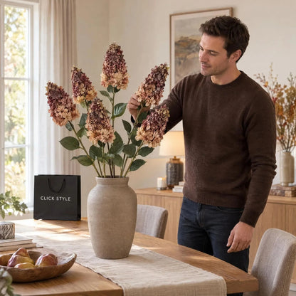 Artificial Burgundy & Peach Long Stem Spear Hydrangea with Realistic Green Leaves – Tall Faux Hydrangea Flower 88cm arranged as five stems in a taupe ceramic vase on an oak dining table with a man adjusting the flowers | Click Style