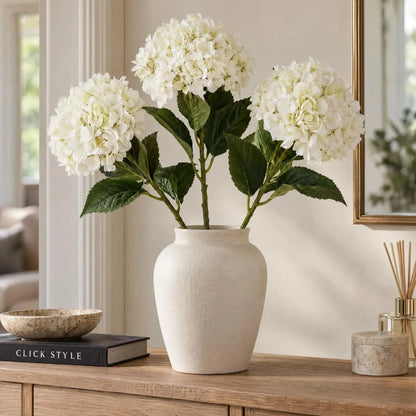 Artificial Creamy White Hydrangea Stem with Full Rounded Bloom & Realistic Green Foliage – Lifelike Faux White Hydrangea Flower 58cm – Three Stems Arranged in an Ivory Ceramic Vase on an Oak Console Table | Click Style