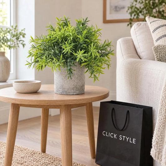 Artificial Green Bamboo Plant with Slender Leaves in Rustic Grey Stone-Effect Pot – Small Realistic Faux Potted Plant 20cm displayed on a round oak side table beside a cream sofa with black CLICK STYLE shopping bag | Click Style