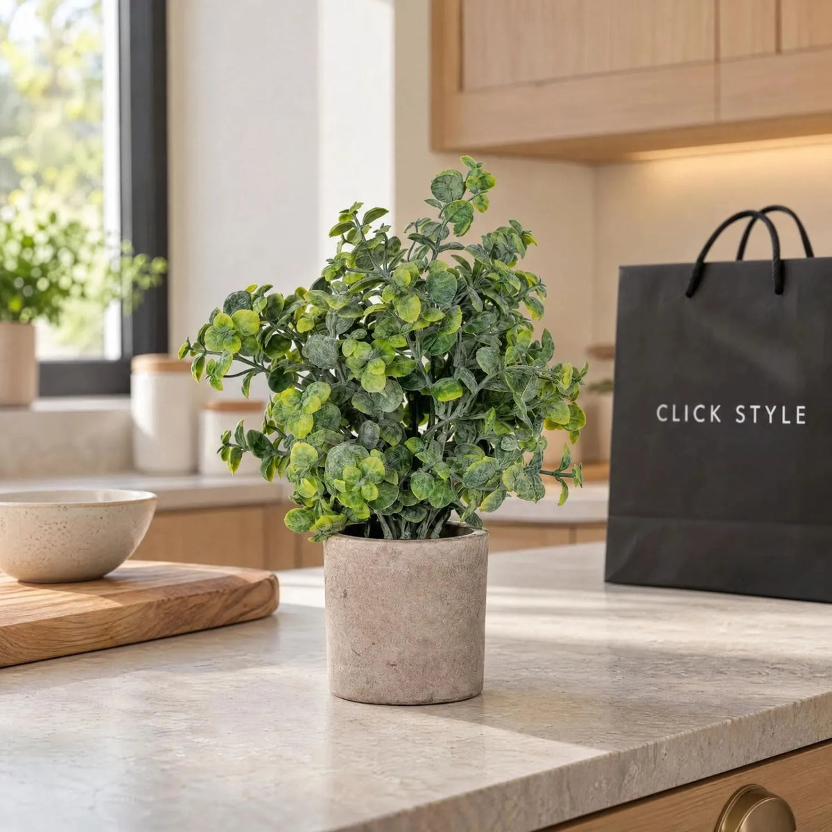 Artificial Green Eucalyptus Plant with Realistic Rounded Leaves in Rustic Stone-Effect Pot – Small Faux Potted Eucalyptus 23x19x19cm displayed on a pale stone kitchen worktop beside a ceramic bowl and black shopping bag with white CLICK STYLE branding | Click Style