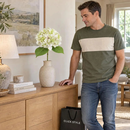 Artificial Pale Green Hydrangea Stem with Multi-Tonal Petals & Realistic Green Leaves – Lifelike Faux Green Hydrangea Flower 50x30x30cm displayed in a stoneware vase on an oak sideboard beside man in green and cream T-shirt with CLICK STYLE shopping bag | Click Style