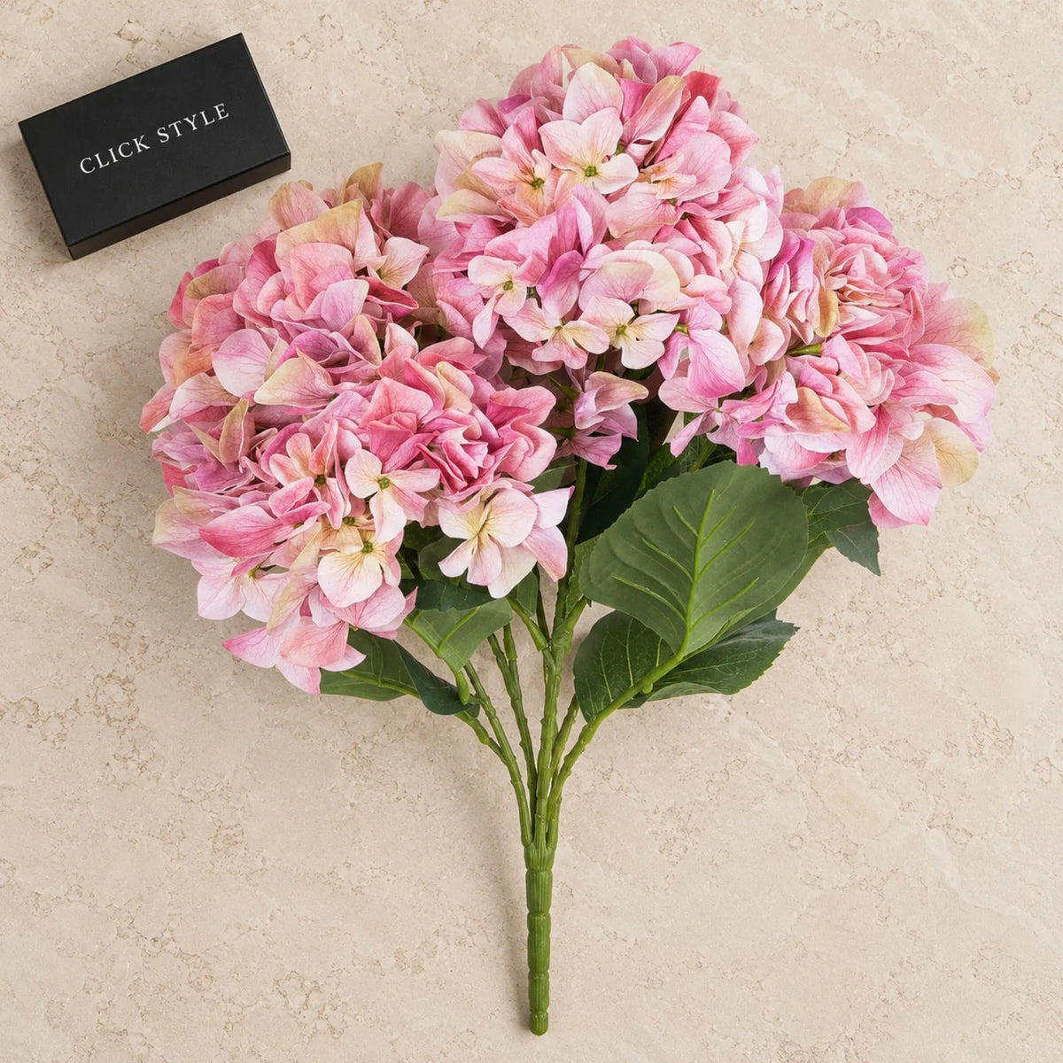 Artificial Pink Multi-Bloom Hydrangea Bouquet Stem with Realistic Green Leaves – Lifelike Faux Pink Hydrangea Flower Arrangement 58x47x47cm displayed on pale limestone with black CLICK STYLE box | Click Style