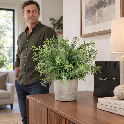 Artificial Rosemary Plant in Grey Stone-Effect Pot with Realistic Green Foliage – Lifelike Faux Potted Herb 24x24x24cm displayed on a walnut sideboard in a contemporary living room with a man standing nearby and black CLICK STYLE shopping bag | Click Style