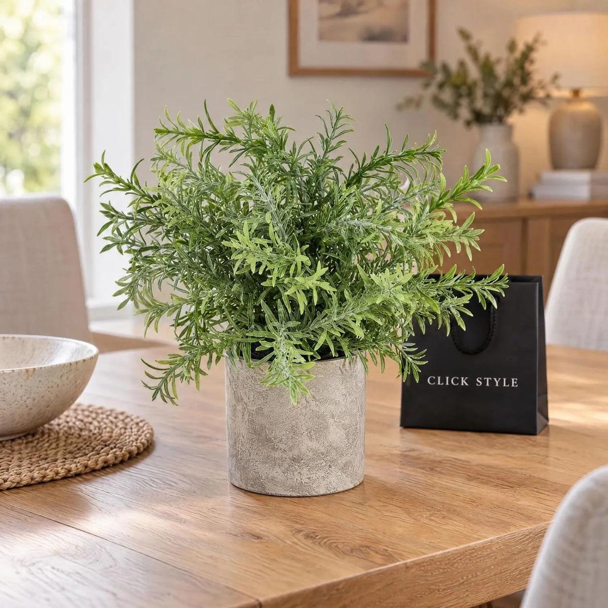 Artificial Rosemary Plant in Grey Stone-Effect Pot with Realistic Green Foliage – Lifelike Faux Potted Herb 24x24x24cm displayed on a natural oak dining table with upholstered chairs and black shopping bag with white CLICK STYLE branding | Click Style