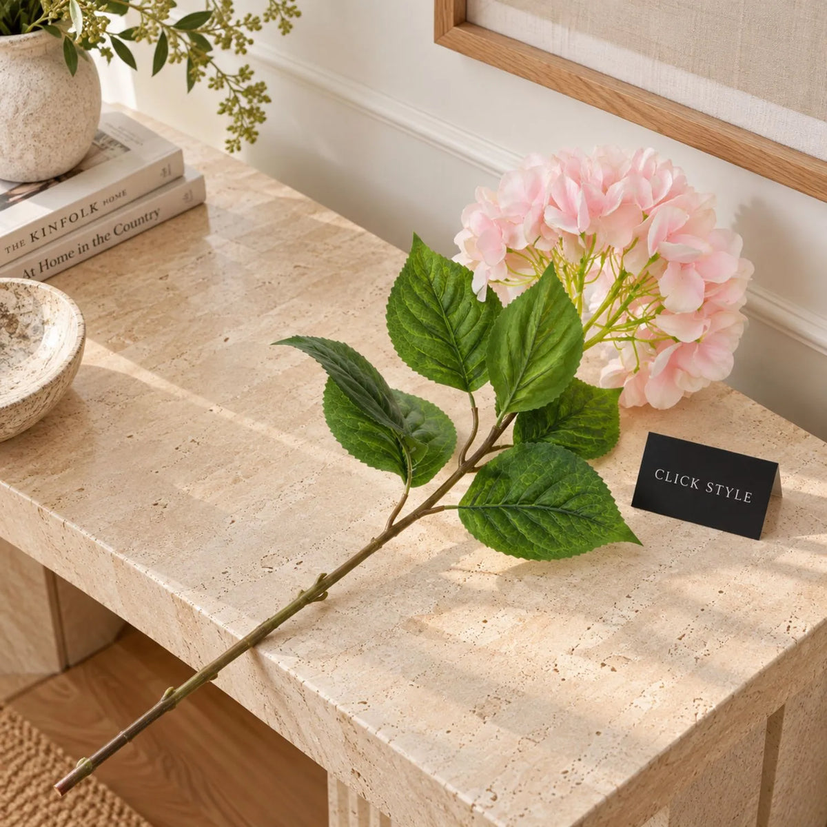 Artificial Soft Pink Long Stem Hydrangea with Full Rounded Flower Head & Realistic Green Leaves – Lifelike Pink Faux Hydrangea Flower 70cm displayed diagonally on a natural travertine table showing delicate blush pink and cream petals, textured green foliage and long wired stem | Click Style