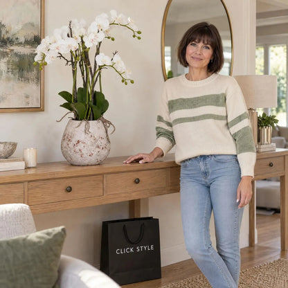 Artificial White Orchid with Cascading Blooms Dark Green Leaves & Realistic Roots in Weathered Stone Effect Pot – Large Potted Faux Orchid Arrangement 70x60x60cm styled on an oak console table beside Abbie with black CLICK STYLE shopping bag | Click Style
