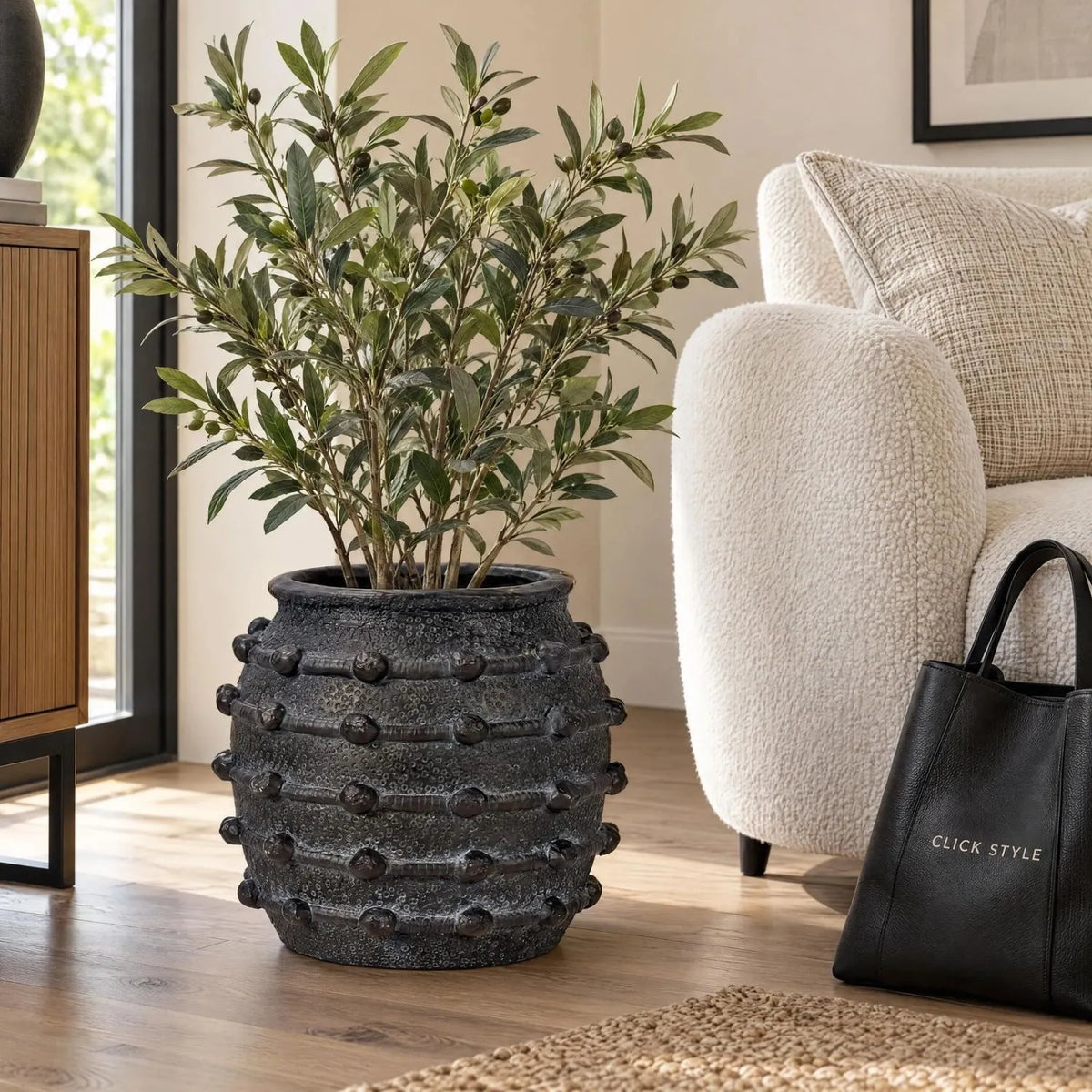 Black Bobbled Fibrestone Planter with Rolled Rim & Raised Textured Detail – Decorative Indoor Plant Pot 29x32x32cm – Artificial Olive Plant Beside Cream Bouclé Chair | Click Style