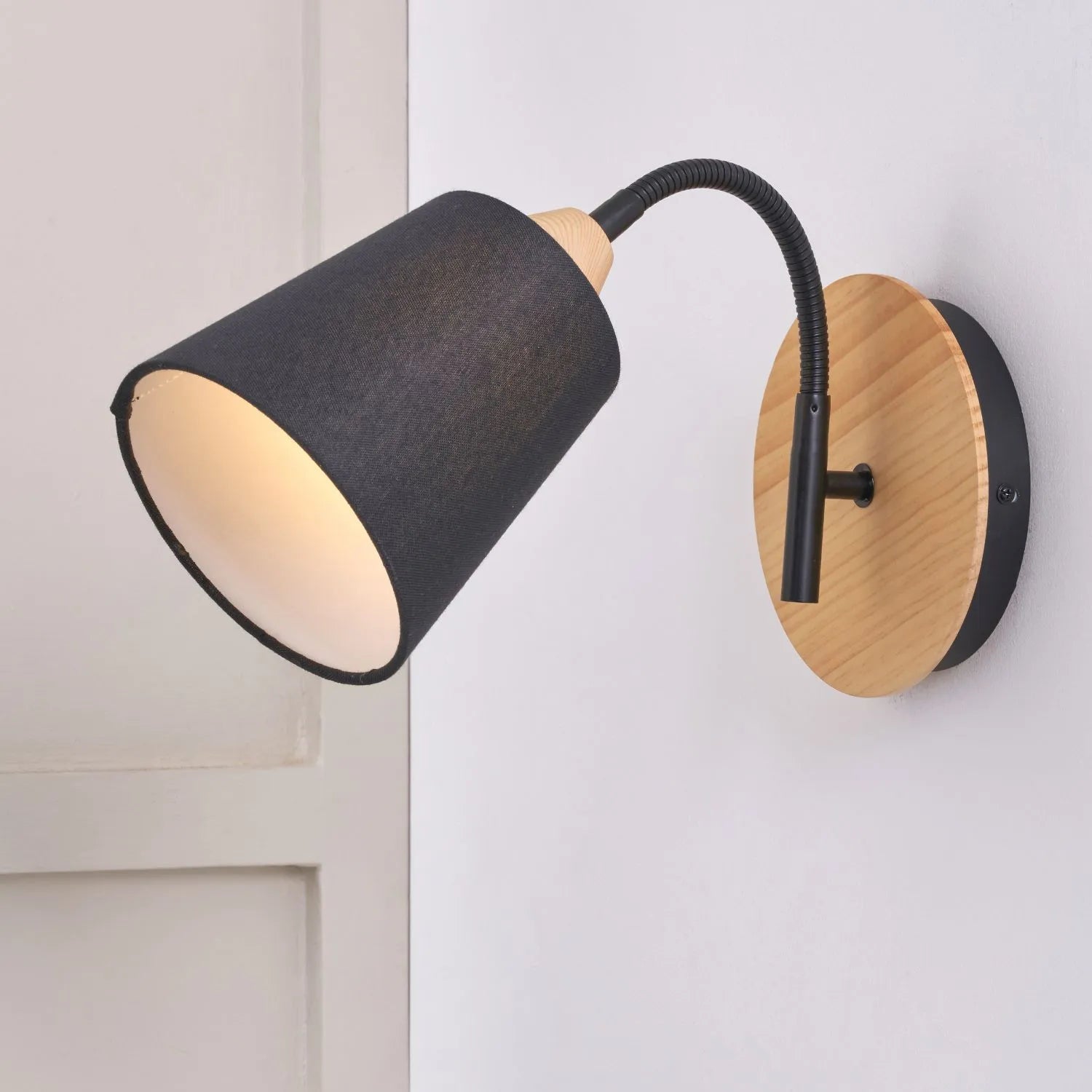 Black metal wall light with adjustable tapered linen shade and natural wood plate – modern bedside reading light | Click Style