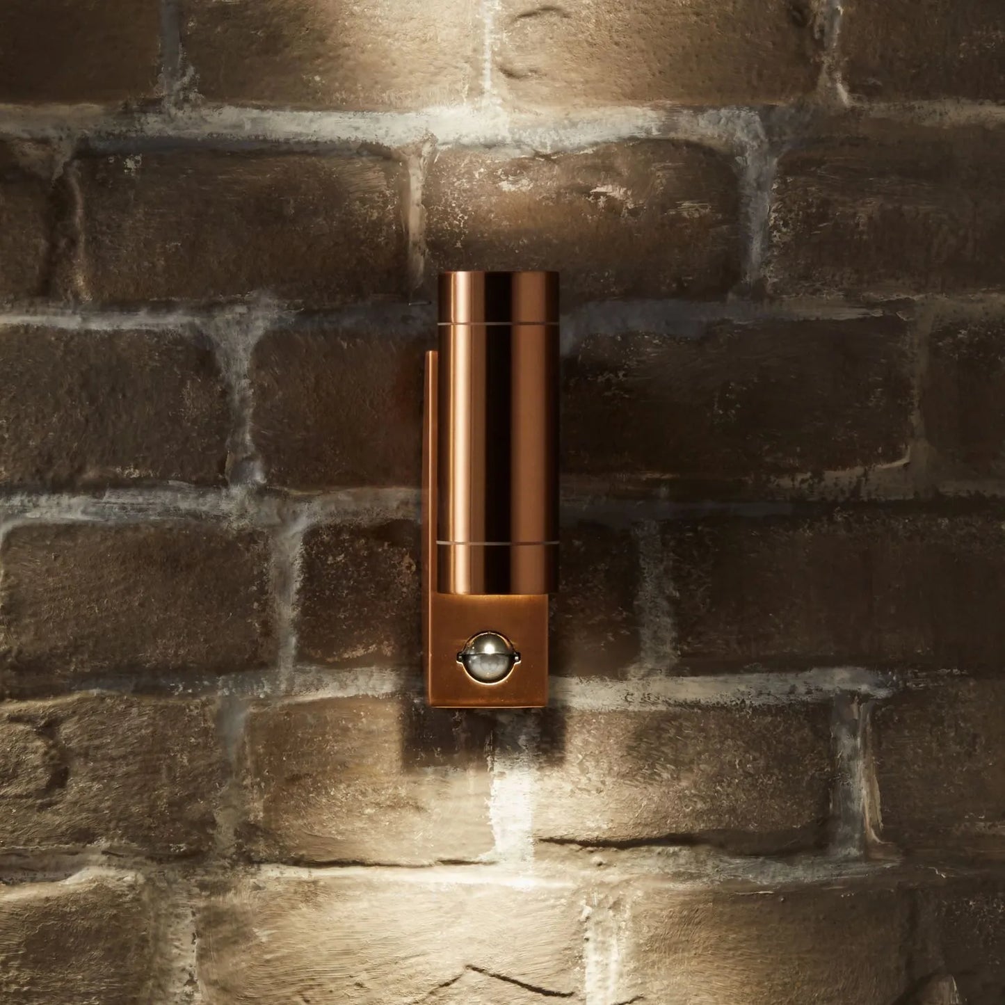 Brushed Copper Outdoor Up & Down PIR Motion Sensor Wall Light Illuminating an Exterior Wall with Dual Up and Down Light Beams | Click Style