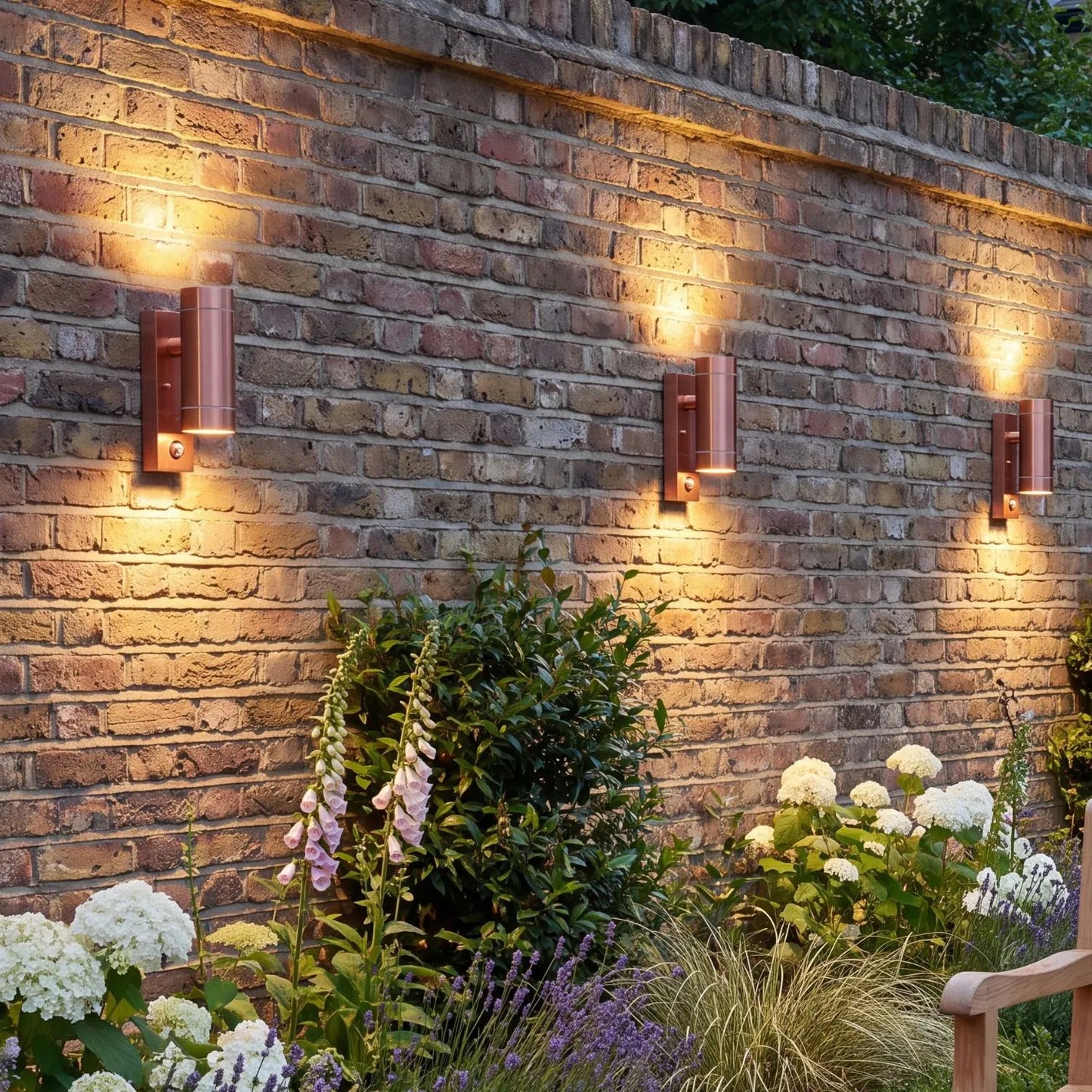 Brushed Copper Outdoor Up & Down PIR Motion Sensor Wall Light Illuminating an Exterior Wall with Dual Up and Down Light Beams | Click Style