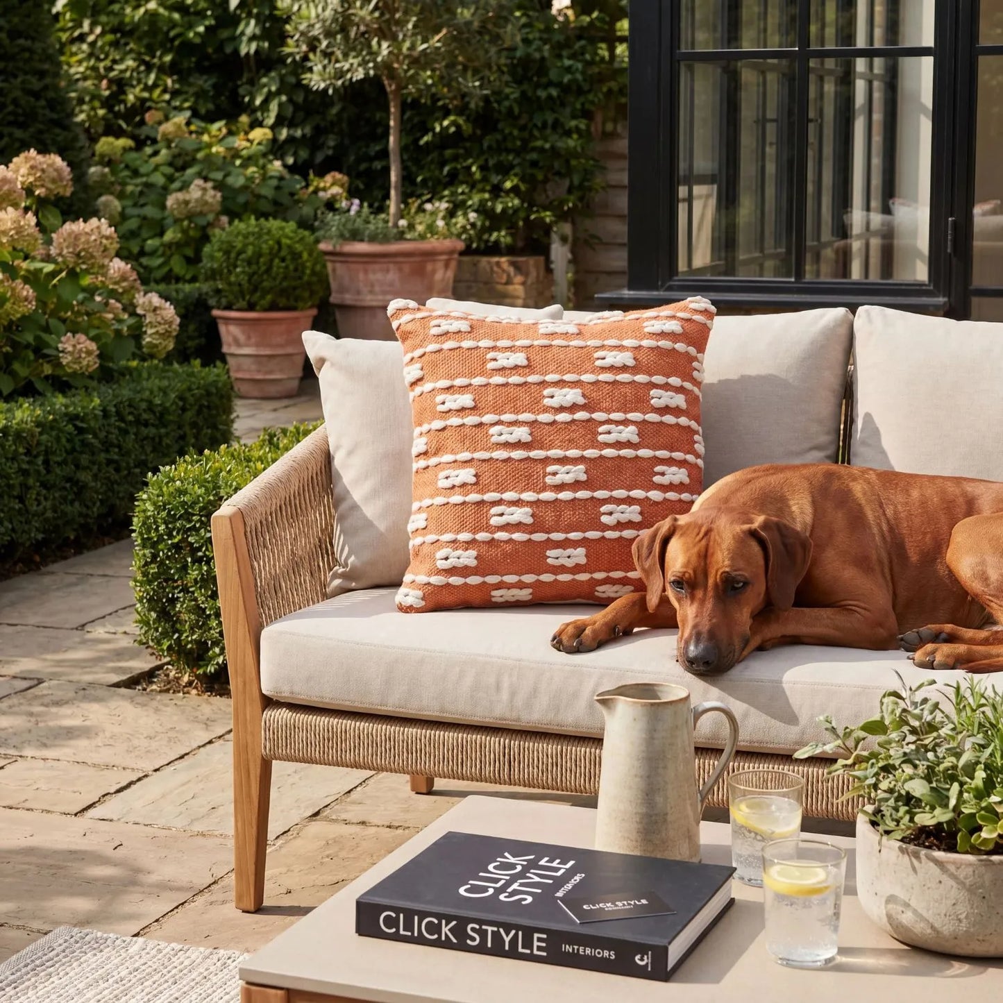 Burnt Orange & White Square Indoor Outdoor Cushion with Braided Bohemian Design – Recycled Weather-Resistant & Durable 45x45x10cm Styled on Garden Furniture in a Patio Seating Area with Warm Terracotta Tones and Natural Outdoor Styling | Click Style