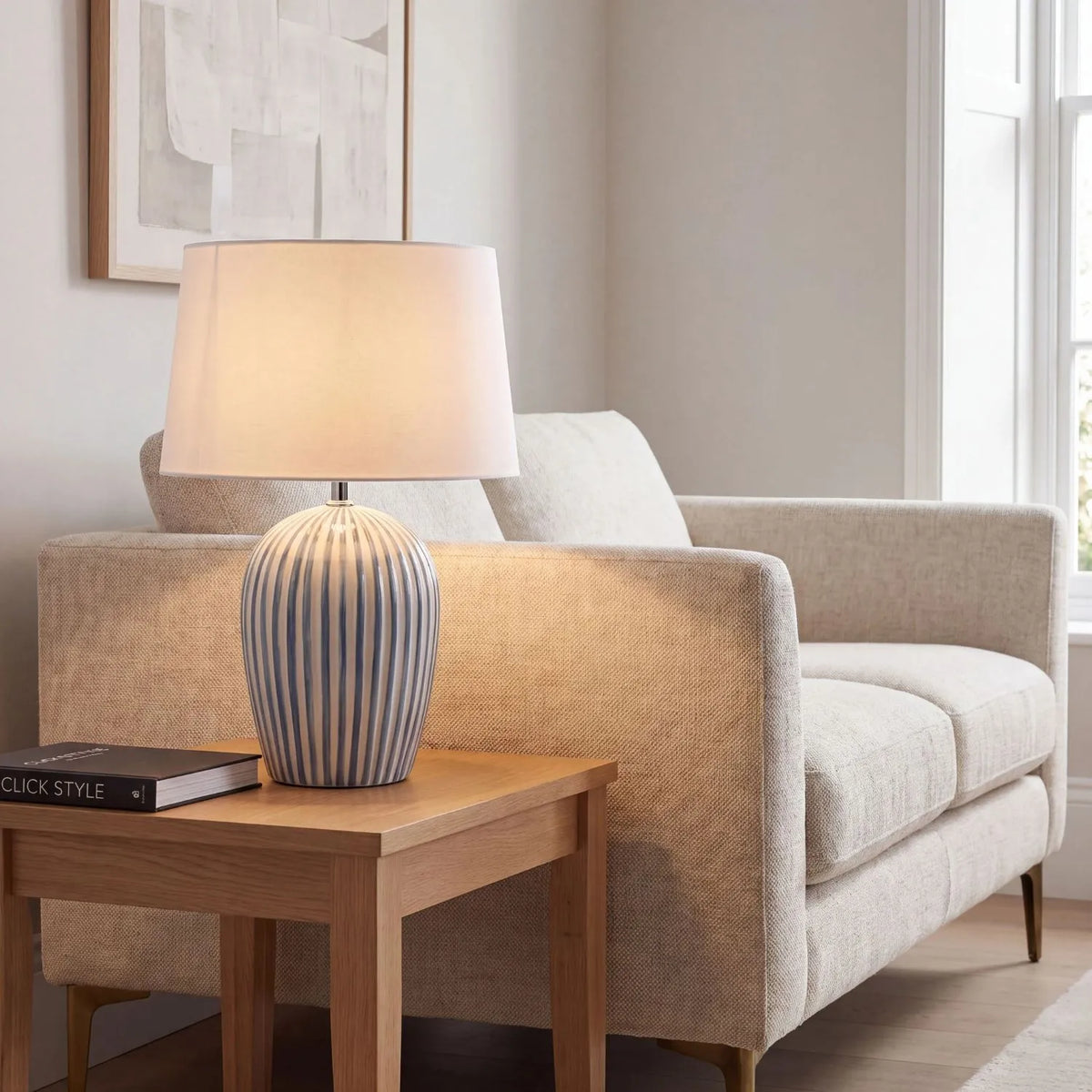 Denim Blue & White Striped Ceramic Table Lamp with White Cotton Tapered Shade – Ribbed Bulbous Base Bedside Light 45x30x30cm styled on a wooden side table beside a neutral sofa in a contemporary living room | Click Style