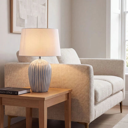 Denim Blue & White Striped Ceramic Table Lamp with White Cotton Tapered Shade – Ribbed Bulbous Base Bedside Light 45x30x30cm styled on a wooden side table beside a neutral sofa in a contemporary living room | Click Style
