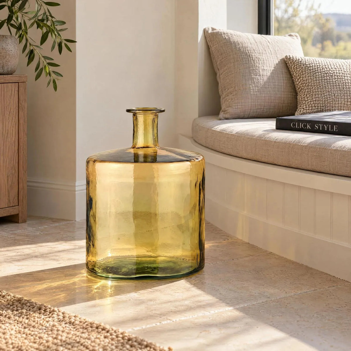 Large Amber Yellow Recycled Glass Bottle Vase with Narrow Neck – Wide Decorative Floor Vase 45x35x35cm – Displayed Empty Beside a Curved Window Seat | Click Style