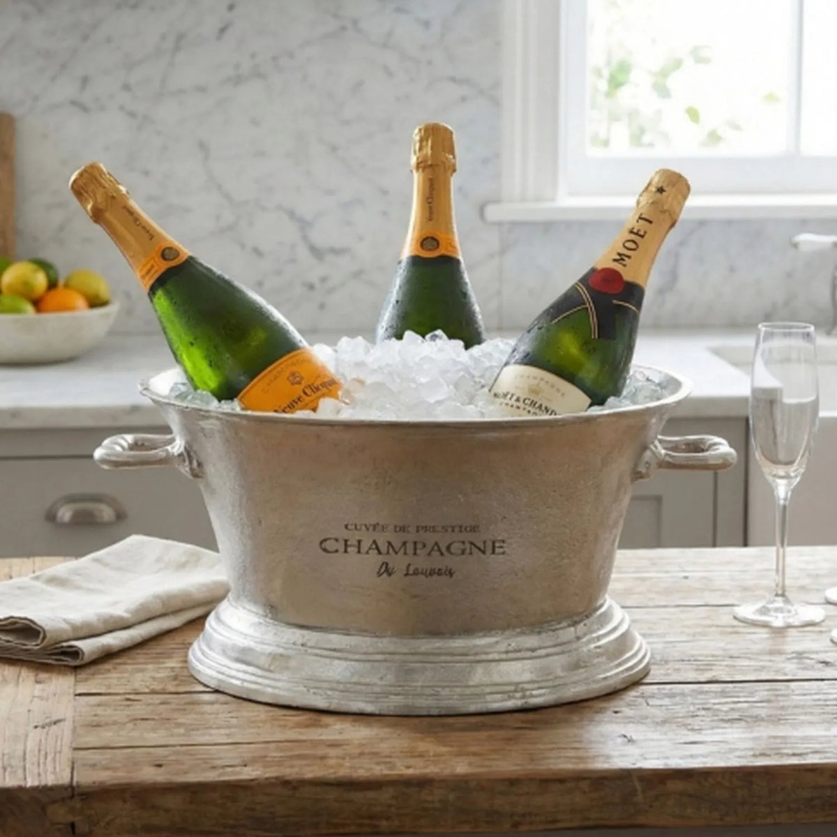 Large Antique Pewter Silver Champagne Cooler with Side Handles – Oval Metal Wine & Prosecco Cooler 23x48x35cm filled with ice and three champagne bottles on a rustic wooden table in a bright kitchen setting | Click Style