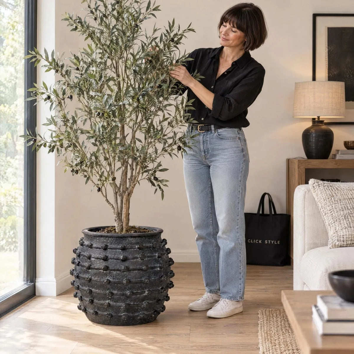 Large Black Bobbled Fibrestone Planter with Rolled Rim & Raised Textured Detail – Decorative Indoor Plant Pot 39x42x42cm – Woman Styling Artificial Olive Tree in Living Room | Click Style