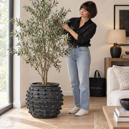 Large Black Bobbled Fibrestone Planter with Rolled Rim & Raised Textured Detail – Decorative Indoor Plant Pot 39x42x42cm – Woman Styling Artificial Olive Tree in Living Room | Click Style