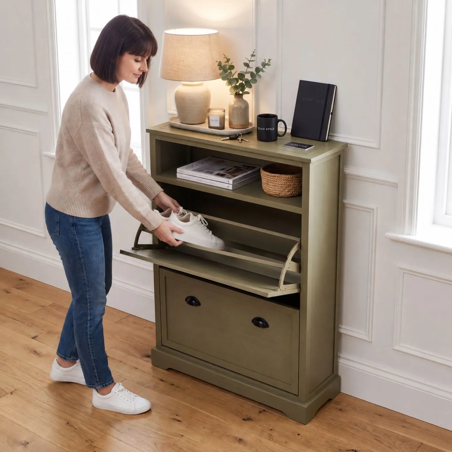 Olive Green Pine Wood 2 Drawer Shoe Storage Unit with Matt Black Cup Handles styled in a modern country hallway with a woman placing trainers into the shoe storage drawer 106x80x28cm | Click Style