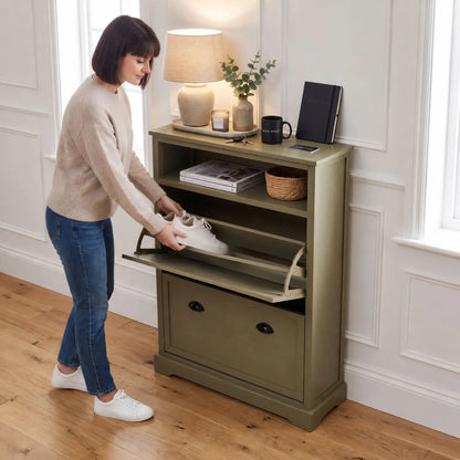 Olive Green Pine Wood 2 Drawer Shoe Storage Unit with Matt Black Cup Handles styled in a modern country hallway with a woman placing trainers into the shoe storage drawer 106x80x28cm | Click Style