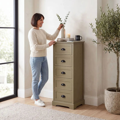 Olive Green Pine Wood 5 Drawer Tall Boy Chest of Drawers with Matt Black Cup Handles styled in a modern country home with a woman arranging eucalyptus stems 108x41x33cm | Click Style