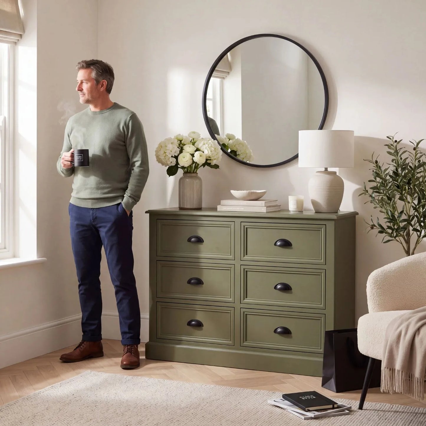 Olive Green Pine Wood 6 Drawer Chest of Drawers with Matt Black Cup Handles Styled in a Modern Country Living Room with Man Holding a Cup of Tea | Click Style