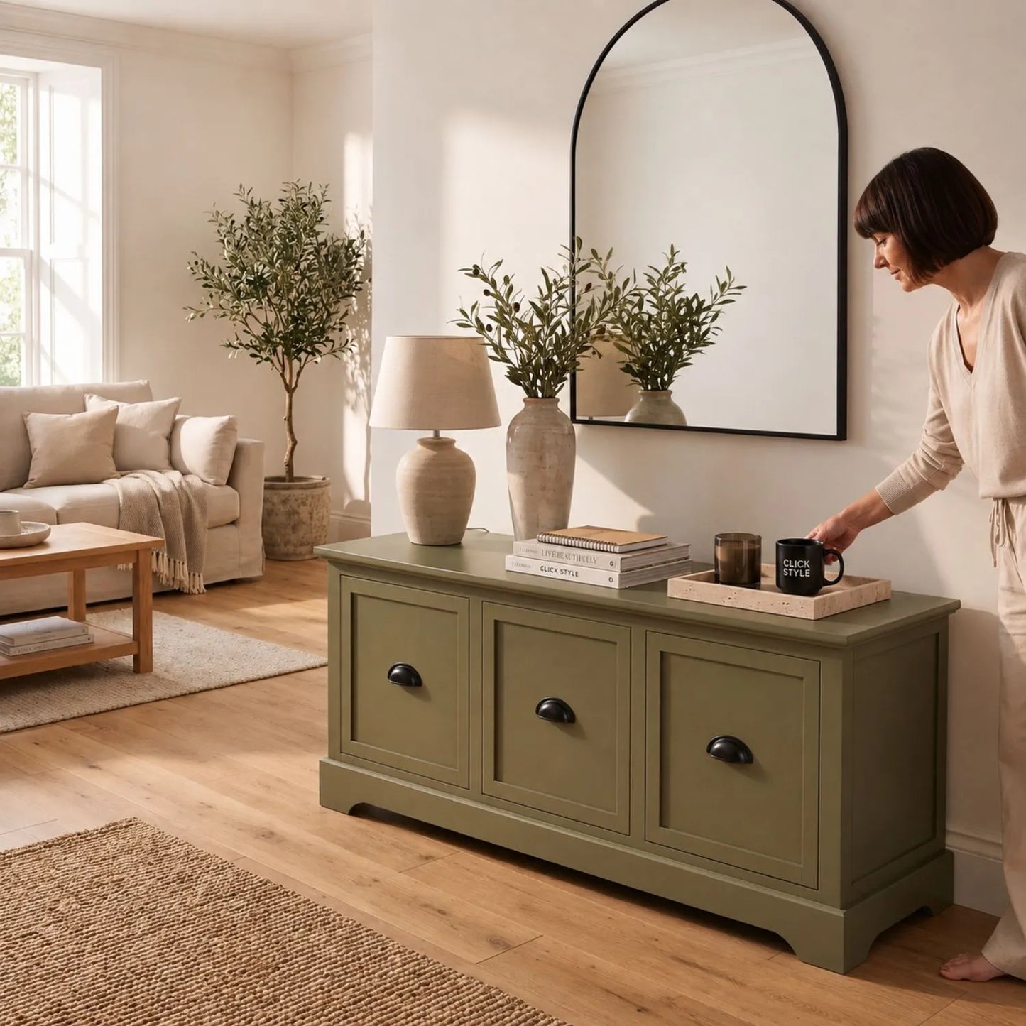 Olive Green Pine Wood Low 3 Drawer Storage Unit with Matt Black Cup Handles styled in a modern country living room with woman arranging framed photograph and decorative accessories | Click Style