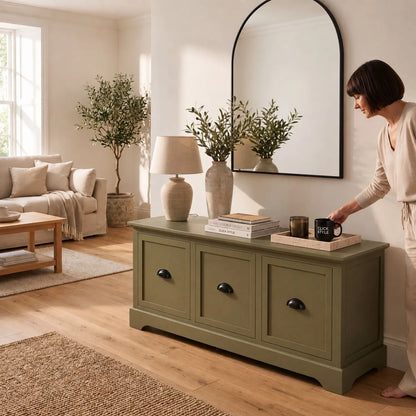 Olive Green Pine Wood Low 3 Drawer Storage Unit with Matt Black Cup Handles styled in a modern country living room with woman arranging framed photograph and decorative accessories | Click Style