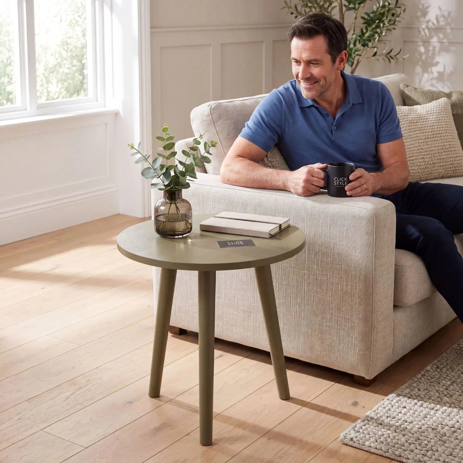 Olive Green Pine Wood Round Tripod Side Table styled in a modern country living room with a man relaxing on a sofa holding a Click Style mug 42x40x40cm | Click Style