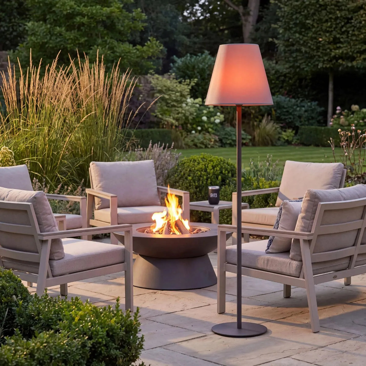 Outdoor Grey Rechargeable LED Floor Lamp with Dimmable & Colour-Changing Settings – Weather-Resistant Garden Light 153x35x35cm glowing warm peach beside outdoor seating and a fire pit in a landscaped garden at dusk | Click Style