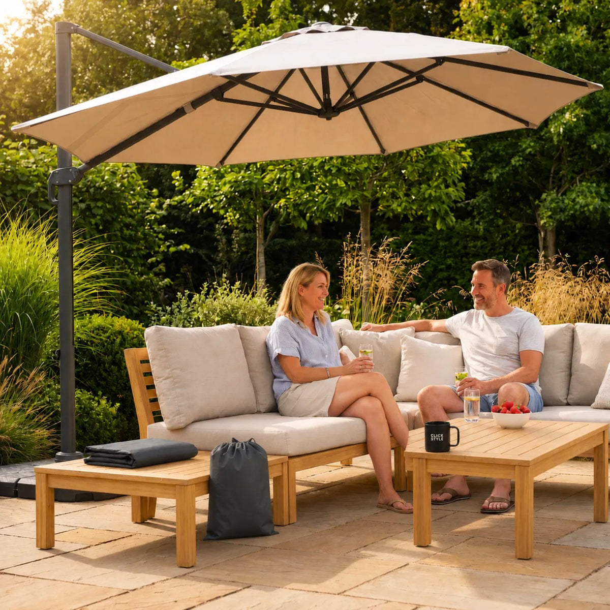 Platinum AeroCover anthracite grey cantilever parasol cover folded with storage bag beside open parasol in UK garden | Click Style