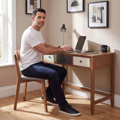 Sage Green & Neutral Pine Wood 3 Drawer Desk with Black Knob Handles styled as a home office desk with man working on a laptop | Click Style