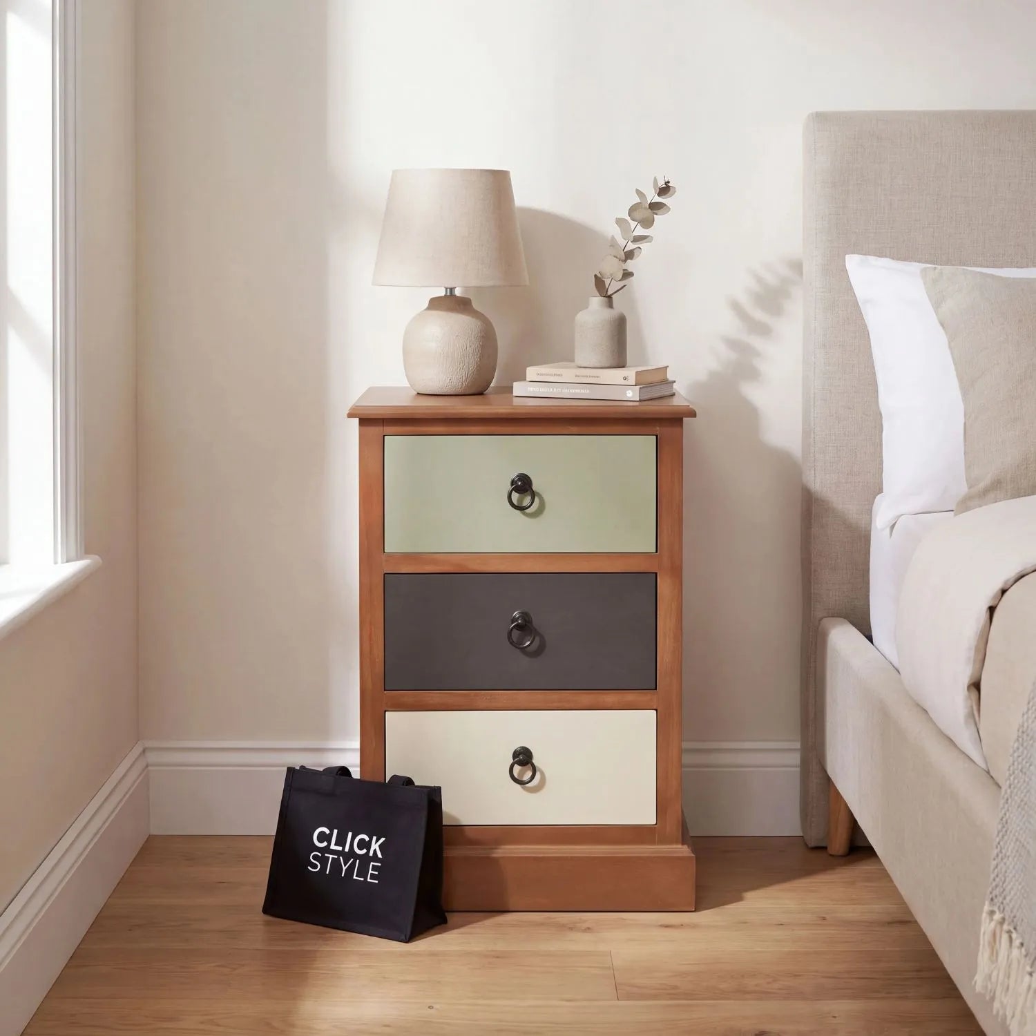Sage green and neutral pine wood 3 drawer side table and bedside table with black ring handles styled beside a neutral bed | Click Style