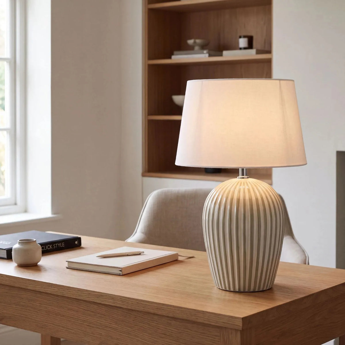 Sage Green & White Striped Ceramic Table Lamp with White Cotton Tapered Shade – Ribbed Bulbous Base Bedside Light 45x30x30cm styled with light on on a natural wood desk in a contemporary home office | Click Style