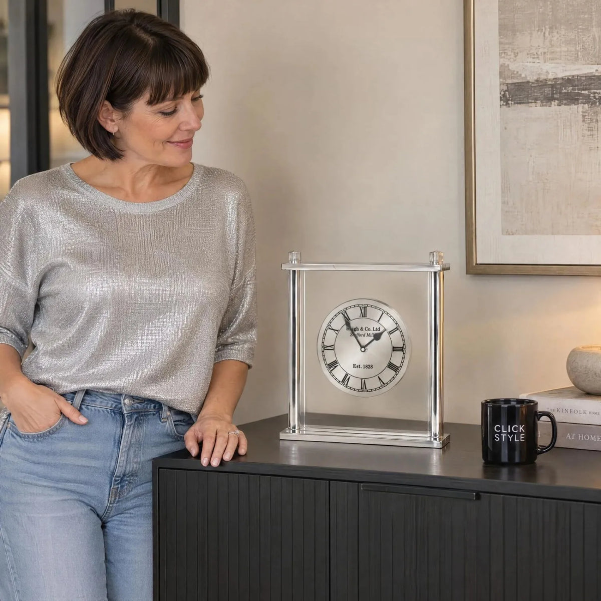 Silver Metal & Glass Table Mantel Clock with Floating Clock Face Roman Numerals & Black Hands 28x25x7cm styled on a charcoal sideboard with Woman from Click Style | Click Style