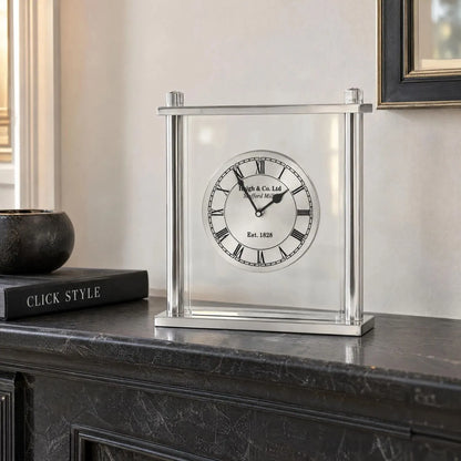 Silver Metal & Glass Table Mantel Clock with Floating Clock Face Roman Numerals & Black Hands 28x25x7cm styled on a dark charcoal mantelpiece with Click Style book | Click Style