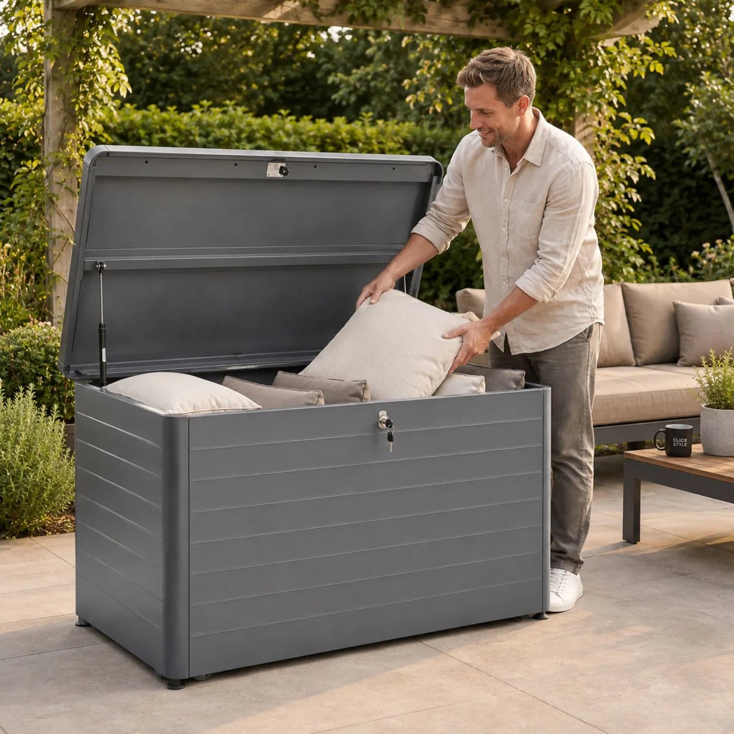 Small Anthracite Grey Galvanised Steel Outdoor Cushion Storage Box with Lockable Lid with man removing garden cushion 78x134x62cm | Click Style