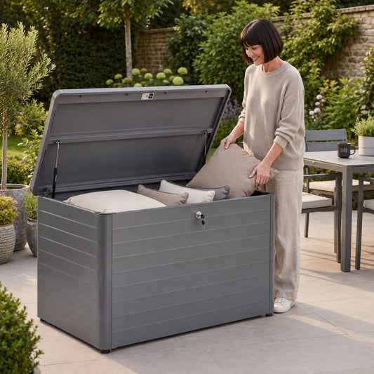 Small Anthracite Grey Galvanised Steel Outdoor Cushion Storage Box with Lockable Lid with woman placing garden cushion inside 78x134x62cm | Click Style
