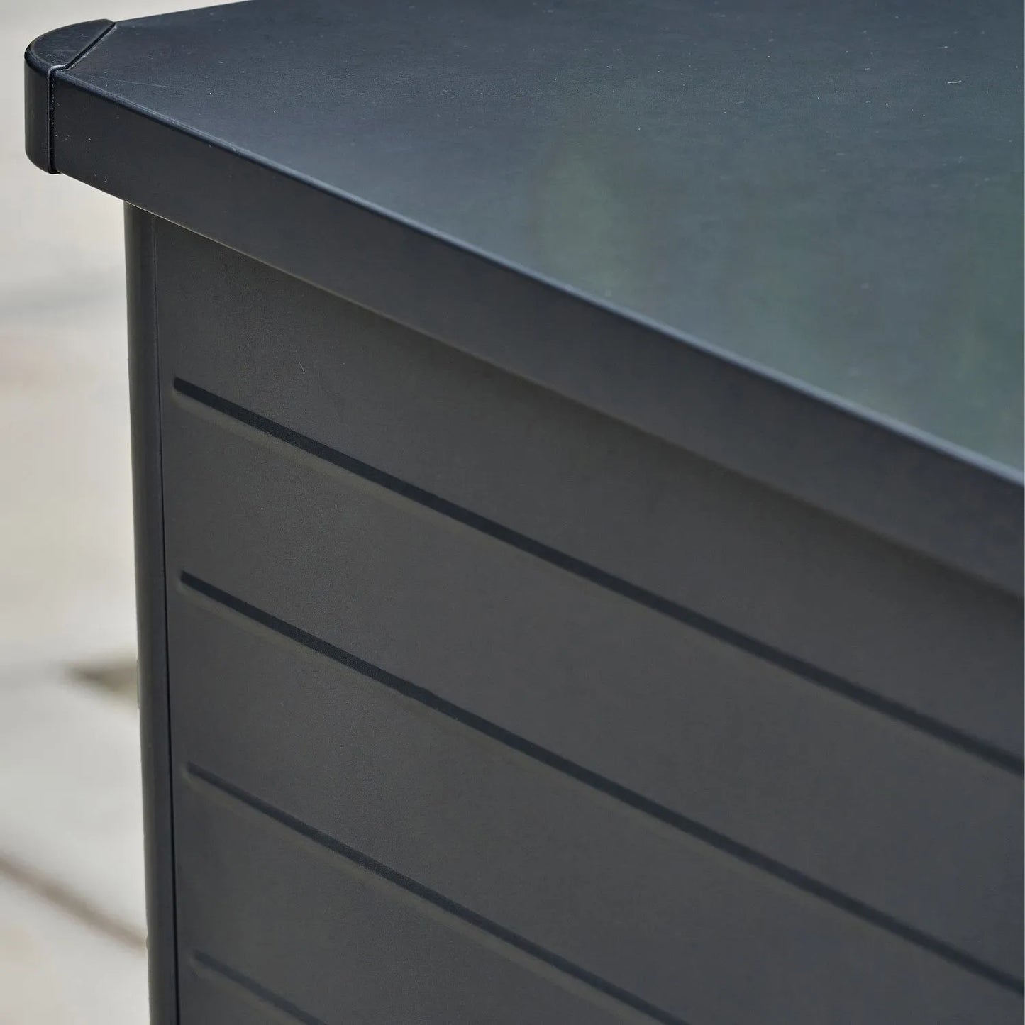 Small Black Galvanised Steel Outdoor Cushion Storage Box lifestyle close-up with closed lid showing rounded top left corner lid and front panel | Click Style
