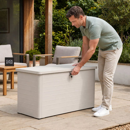 Small Light Grey Pebble Galvanised Steel Outdoor Cushion Storage Box with closed lockable lid and man using the key styled in a contemporary garden with Click Style branding | Click Style
