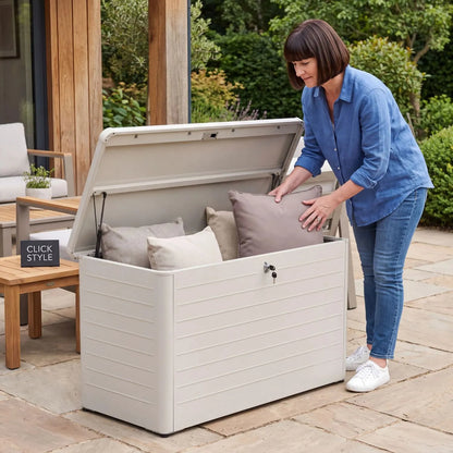 Small Light Grey Pebble Galvanised Steel Outdoor Cushion Storage Box with open lid and woman placing a garden cushion inside in a contemporary garden | Click Style