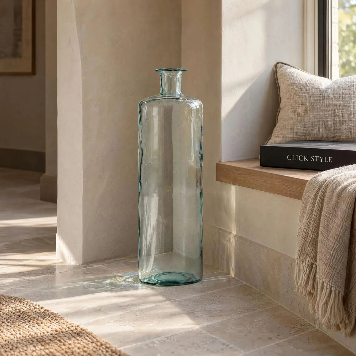 Tall Clear Recycled Glass Bottle Vase with Narrow Neck – Large Decorative Floor Standing Vase 75x25x25cm – Displayed Empty Beside a Window Seat in a Warm Neutral Interior | Click Style