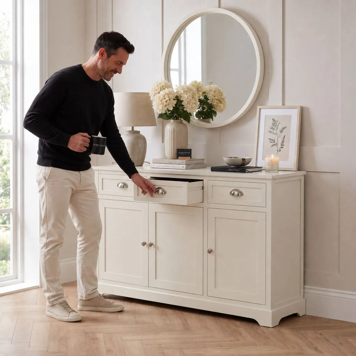 Warm Ivory Pine Wood 3 Door 3 Drawer Sideboard with Silver Cup Handles styled in a neutral home with a man 75x120x35cm | Click Style