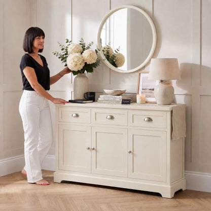 Warm Ivory Pine Wood 3 Door 3 Drawer Sideboard with Silver Cup Handles styled in a neutral home with a woman 75x120x35cm | Click Style
