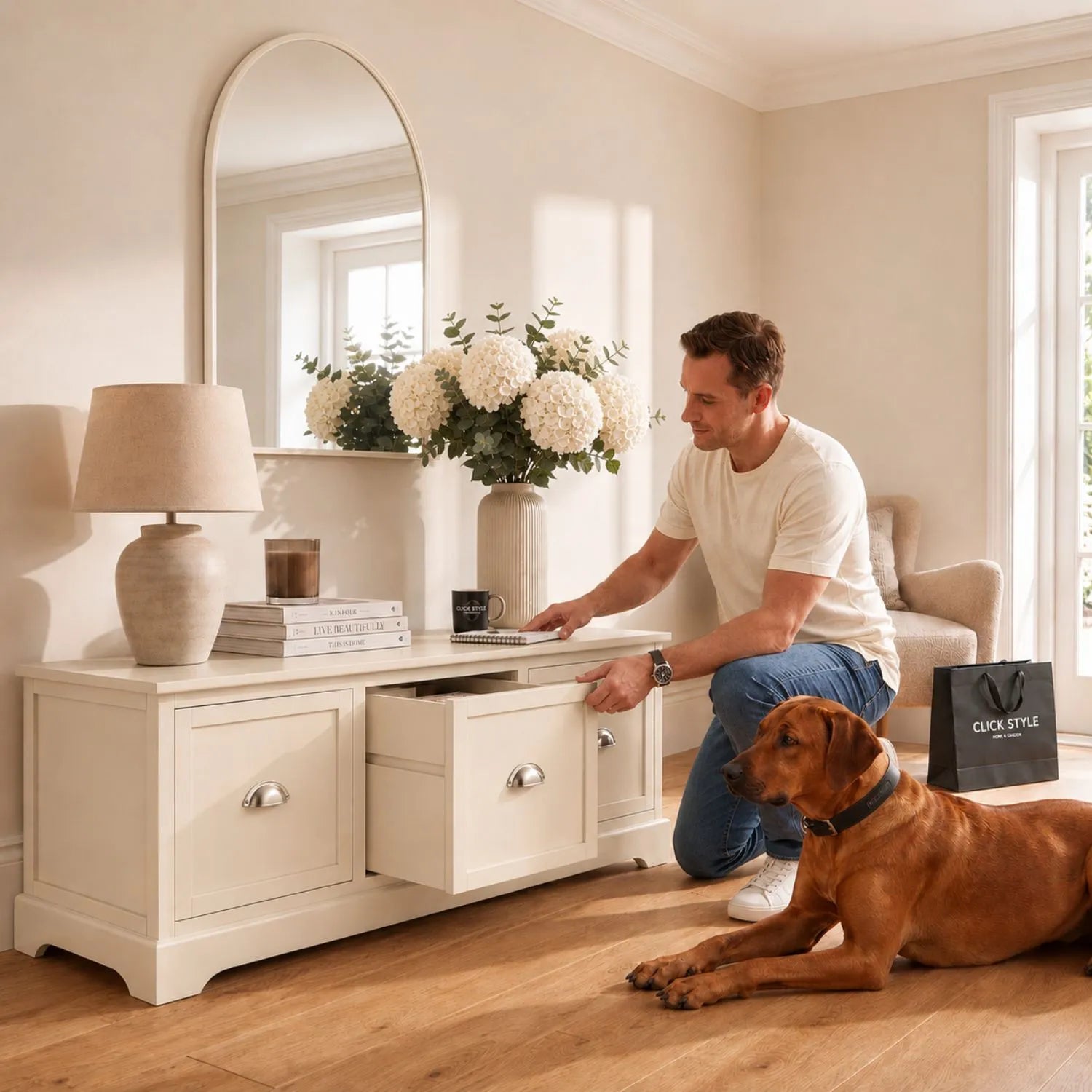 Warm Ivory Pine Wood Low 3 Drawer Storage Unit with Polished Silver Cup Handles with man opening middle drawer and Rhodesian Ridgeback 48x107x39cm | Click Style